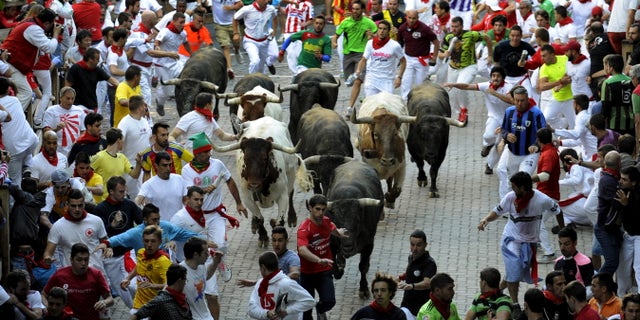 July 14, 2015 - FILE photo of runners sprinting alongside Miura fighting bulls at the entrance to the bullring on the last day of the running of the bulls of the San Fermin festival in Pamplona, northern Spain. A Spanish mayor says a man has died after being gored while videoing a bull-run with his cell phone.