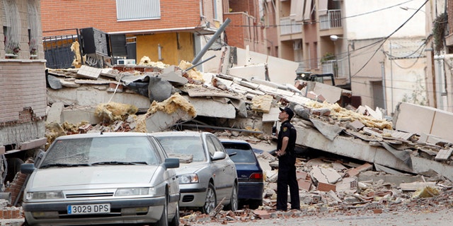 May 12, 2011: A police officer inspects damage caused by an earthquake the previous day in Lorca, Spain. Farmers drilling ever deeper wells over decades to water their crops likely contributed to the deadly earthquake in southern Spain last year, a new study suggests.