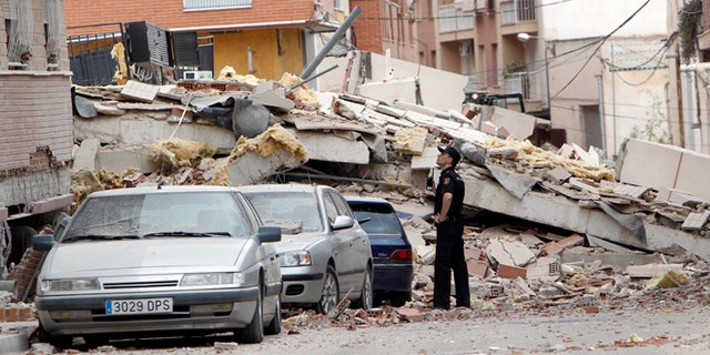 May 12, 2011: A police officer inspects damage caused by an earthquake the previous day in Lorca, Spain. Farmers drilling ever deeper wells over decades to water their crops likely contributed to the deadly earthquake in southern Spain last year, a new study suggests.