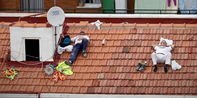 In this Oct. 10, 2012 file photo, workers take a nap on a roof in Madrid, Spain.