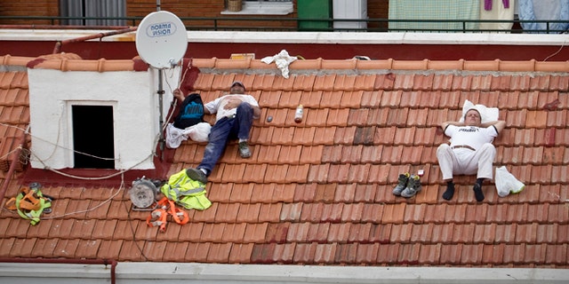 In this Oct. 10, 2012 file photo, workers take a nap on a roof in Madrid, Spain.