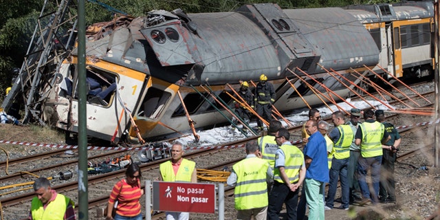 Emergency personnel attend the scene after a passenger train traveling from Vigo to Porto, in neighboring Portugal, derailed in O Porrino, in Spain's northwestern Galicia region, killing and injuring people, authorities said Friday Sept. 9, 2016. The train had three cars. The front one came completely off the track and hit a post next to the line, leaving it leaning to one side. The back two cars were partly off the tracks. Spanish media said the train was carrying around 60 passengers.(AP Photo/Lalo R. Villar)