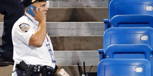 In this photo taken on Thursday, Sept. 3, 2015, police officers investigate the southwest corner of Louis Armstrong Stadium after a drone flew over the court, buzzing the players during a match between Flavia Pennetta, of Italy, and Monica Niculescu, of Romania, during the second round of the U.S. Open tennis tournament in New York. The drone crash-landed in the seats and can be seen to the right of the police officer on his phone. Whether they're crashing into the bleachers or simply hovering above stadiums to get a cool picture of the action down below, drones have become semi-regular guests at the ballparks these days. That has put the federal government, local police forces and security think tanks on alert, trying to catch up to the technology and figure out how to prevent the hard-to-stop devices from doing major damage. (AP Photo/Kathy Willens)