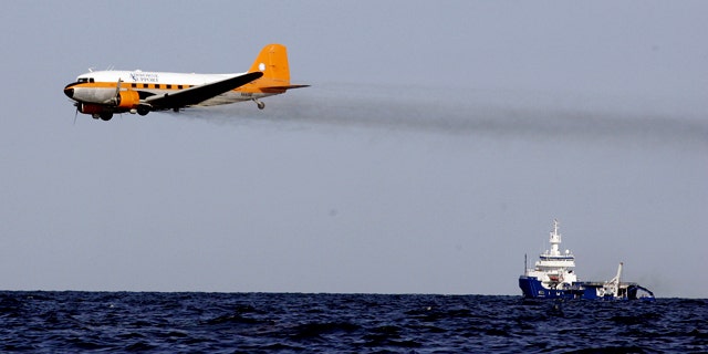 A dispersant plane passes over an oil skimmer as it cleans oil from a leaking pipeline that resulted from last week's explosion and collapse of the Deepwater Horizon oil rig in the Gulf of Mexico near the coast of Louisiana Tuesday, April 27, 2010.
