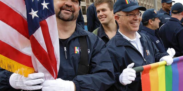 FILE - In this Nov. 11, 2014 file photo, retired U.S. Air Force Master Sgt. Eric Bullen, of Westborough, Mass., left, holds an American flag as U.S. Army veteran Ian Ryan, of Dennis, Mass., front right, rolls up an OutVets banner after marching with a group representing LGBT military veterans in a Veterans Day parade in Boston. The organizers of Boston's annual St. Patrick's Day parade voted to allow the group of gay veterans along with a second gay group, Boston Pride, to march in the parade scheduled to step off at 1 p.m., on Sunday, March 15, 2015. (AP Photo/Steven Senne, File)