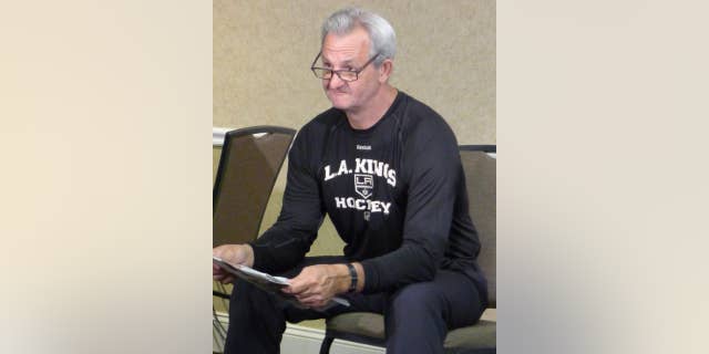 Coach Darryl Sutter looks up from reading the paper before his media availability at a hotel adjacent to the Kings' practice facility in El Segundo, Calif., on Friday, June 6, 2014. (AP Photo/The Canadian Press, Neil Davidson)