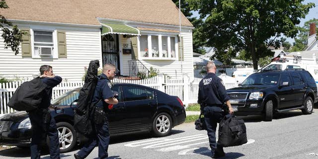 New York City Police Department Emergency Service members carry their gear as they leave the scene of a standoff, Friday, Aug. 14, 2015, in the Staten Island borough of New York. Garland Tyree, a high-ranking member of the Bloods street gang who was to be arrested on parole violations when he shot a firefighter responding to a call of smoke coming from his girlfriend's home, died Friday in a gunfight with police after a six-hour standoff, two police officials said. (AP Photo/Mary Altaffer)