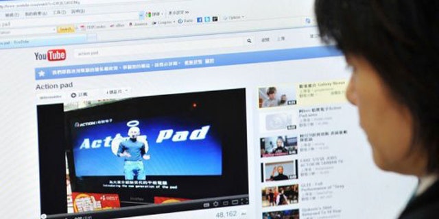 A woman looks at an Internet website in Taipei showing Taiwanese comedian A-Ken dressed up as Apple's late founder.