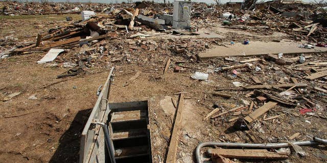 FILE - In this May 26, 2013, file photo, an underground shelter is seen near tornado rubble in Moore, Okla. The deadly tornadoes that killed more than 30 people scared Oklahomans in a way that previous storms had not, moving them to add tornado shelters or reinforced safe rooms to their homes. But the surge of interest in tornado safety has overwhelmed companies that build the shelters. Now there are long waiting lists, and many people have to endure the most dangerous part of the season with no added protection. (AP Photo/Charlie Riedel, File)