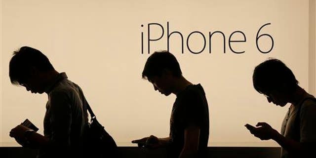 In this photo taken on Friday, Sept. 19, 2014, people wait outside an Apple store in Hong Kong.
