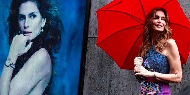 Cindy Crawford holds an umbrella as she poses for photographs at a promotional event for Omega���s new Constellation Pluma Collection in Mumbai, India, Thursday, June 18, 2015.