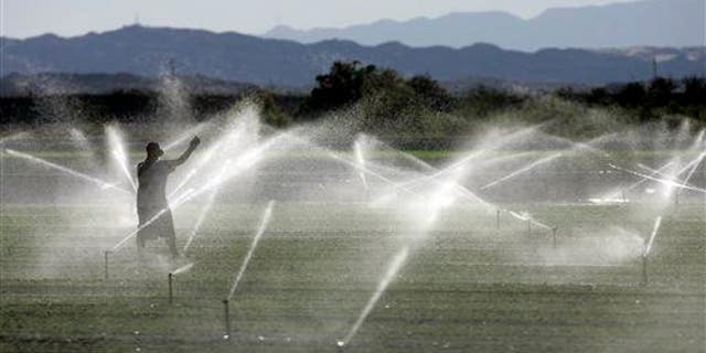 A farm worker adjusts an irrigation system in California. A new study found we're using up Earth's groundwater supply faster than it's being replenished.