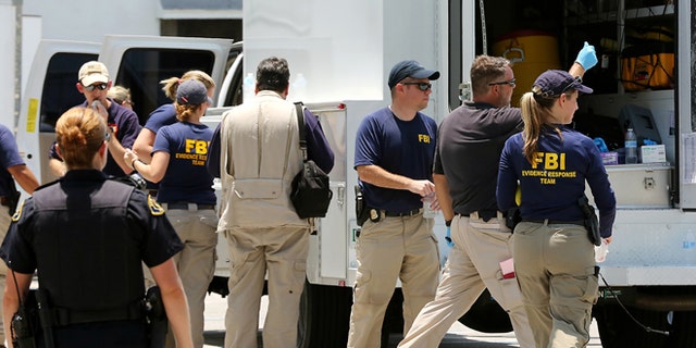 In this photo taken on Monday, July 27, 2015, federal agents and Key West Police gather in a restaurant parking lot in Key West, Fla. A man described by the FBI as an Islamic State sympathizer who hoped to mount attacks on U.S. soil was charged Tuesday with plotting to detonate a nail-filled backpack bomb on a Florida beach. (Rob O'Neal/The Key West Citizen via AP) MIAMI OUT; MANDATORY CREDIT