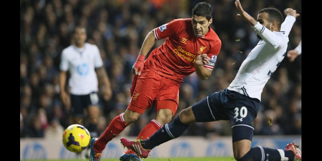 Liverpool's Luis Suarez, left, shoots and scores the opening goal during their English Premier League soccer match between Tottenham Hotspur and Liverpool at the White Hart Lane stadium in London Sunday, Dec. 15, 2013. (AP Photo/Alastair Grant)