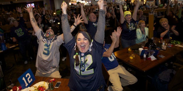 February 2, 2014: Seattle Seahawks fans Brittney Gutierrez, center, and her husband Mike Gutierrez, left, celebrate while watching Super Bowl XLVIII at Big Al's in Vancouver, Wash. Seattle defeated the Denver Broncos 43-8. (AP Photo/The Columbian, Steven Lane)