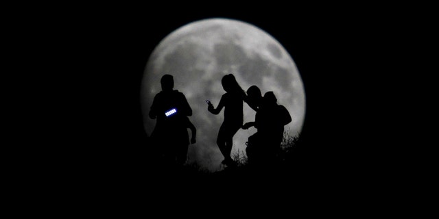 File photo - A group of hikers are seen silhouetted against the moon in Tijuana, Mexico, Aug. 27, 2015.