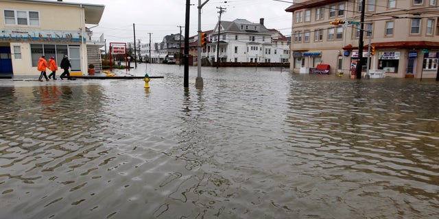 People walk along a flooded intersection of 8th Street and Atlantic Avenue, in Ocean City, N.J., Tuesday, Oct. 30, 2012, after the storm surge from Sandy flooded much of the town. Sandy, the storm that made landfall Monday, caused multiple fatalities, halted mass transit and cut power to more than 6 million homes and businesses. (AP Photo/Mel Evans)