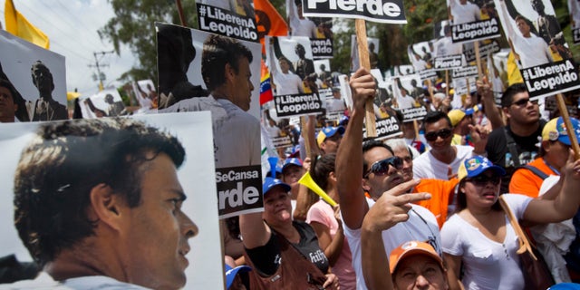 Supporters of jailed opposition leader Leopoldo Lopez gather for a demonstration to mark one month of his detention, near the Cabo Verde jail where he is being held, in Los Teques, Venezuela, Tuesday, March 18, 2014. Lopez handed himself in to the authorities on February 18 after coming out of hiding to attend a rally of supporters in Caracas. The Harvard-educated politician has been accused of terrorism for encouraging anti-government protests. (AP Photo/Esteban Felix)