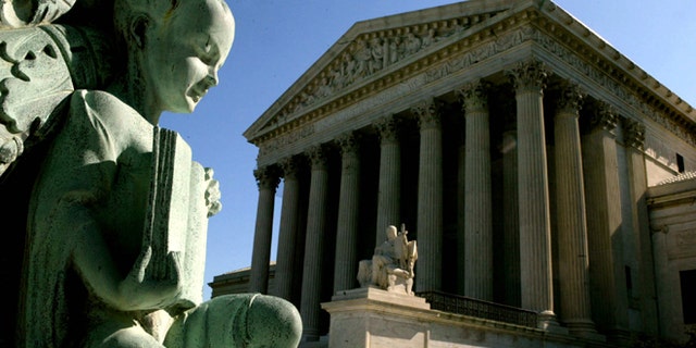WASHINGTON - APRIL 28: A statue at the base of a flagpole stands outside the U.S. Supreme Court April 28, 2004 in Washington, DC. Today the high court heard arguments on the jailing of American citizens suspected of links to terrorism and denying them access to lawyers and courts. (Photo by Mark Wilson/Getty Images)