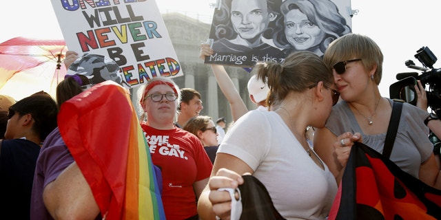 American University students Sharon Burk, left, and Molly Wagner participate in a rally for rights for gay couples in front of the Supreme Court in Washington.