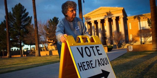 PHOENIX, AZ - FEBRUARY 28:  Election day volunteer Vicki Groff places a sign to direct voters to a polling station at Kenilworth School February 28, 2012 in Phoenix, Arizona. Voters in this state participate in choosing who will be the Republican candidate to contest President Barack Obama in the general election.  (Photo by Jonathan Gibby/Getty Images)
