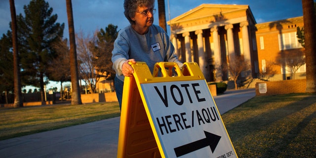 PHOENIX, AZ - FEBRUARY 28: Election day volunteer Vicki Groff places a sign to direct voters to a polling station at Kenilworth School February 28, 2012 in Phoenix, Arizona. Voters in this state participate in choosing who will be the Republican candidate to contest President Barack Obama in the general election. (Photo by Jonathan Gibby/Getty Images)