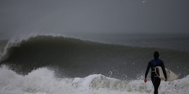 CAPE MAY, NJ - OCTOBER 28: A surfer walks into the heavy surf caused by approaching hurricane Sandy, on October 28, 2012 in Cape May, New Jersey. Hurricane Sandy is expected to hit the New Jersey coastline sometime on Monday bringing heavy winds and floodwaters. (Photo by Mark Wilson/Getty Images)