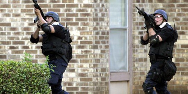 Members of a SWAT unit take aim at a second floor apartment window during a 2006 standoff in which a shooter wounded three police officers and a state trooper.