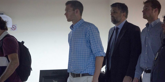 Accompanied by Brazilian lawyer Sergio Riera, second from right, American Olympic swimmers Gunnar Bentz, left, and Jack Conger, right, leave a police station in the Leblon neighborhood of Rio de Janeiro, Brazil, Thursday, Aug. 18, 2016. The two were taken off their flight from Brazil to the U.S. on Wednesday by local authorities amid an investigation into a reported robbery targeting Ryan Lochte and his teammates. A Brazilian police officer told The Associated Press that Lochte fabricated a story about being robbed at gunpoint in Rio de Janeiro. (AP Photo/Mauro Pimentel)