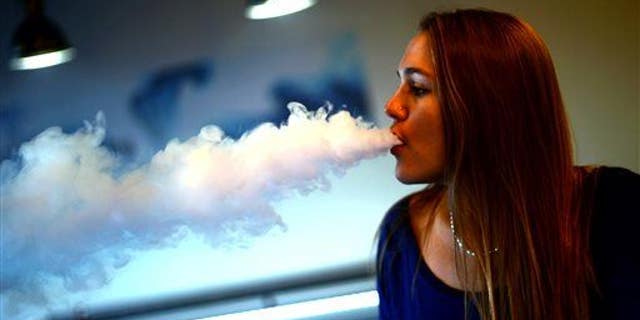 This Nov. 26, 2013 photo shows Steffani Leifeld exhaling a vapor at the Smokeless Smoking electronic cigarette store in Woodbury, Minn.
