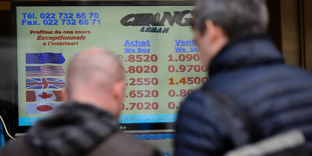 People line up at a currency exchange office, Thursday, Jan.15, 2015 in Geneva Switzerland. Switzerland's central bank said it has scrapped a policy that limited how much the euro could fall against the Swiss franc, an unexpected decision that caused gyrations in financial markets. The move to ditch the policy — which ensured the euro did not fall below 1.20 francs — sent the euro plummeting a stunning 30 percent against the Swiss currency before it recovered somewhat. By later morning, it was down 13 percent at 1.04 francs. (AP Photo/Keystone,Martial Trezzini)