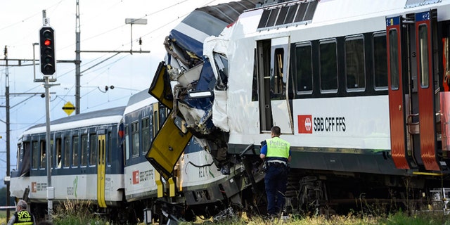 July 29, 2013: Police inspect the site where two passenger trains collided head-on in Granges-pres-Marnand, western Switzerland. Numerous people have been injured.