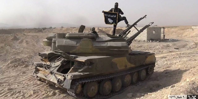 An ISIS militant stands on a tank captured from Syrian government forces, in Qaryatain, central Syria. (Photo released Aug. 5, 2015 by Rased News Network, a Facebook page affiliated with ISIS/via AP)