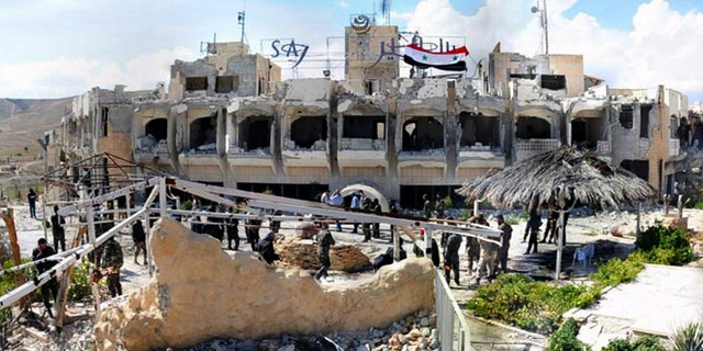 April 14, 2014: This photo, released by the Syrian official news agency SANA, shows Syrian government soldiers gathering outside a damaged hotel that Syrian rebels had been using, in Maaloula village, northeast of the capital Damascus, Syria.