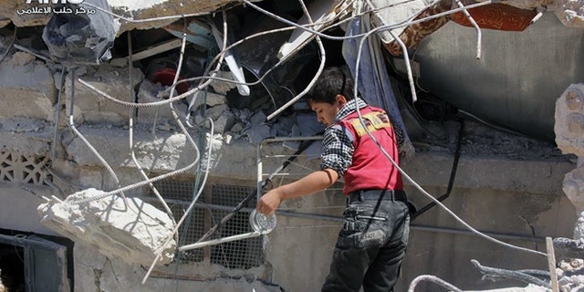 May 18, 2014: This photo provided by the anti-government activist group Aleppo Media Center (AMC), which has been authenticated based on its contents and other AP reporting, shows a Syrian young inspecting the rubble of houses that were destroyed by airstrikes from the Syrian government forces in Aleppo, Syria. (AP/Aleppo Media Center, AMC)