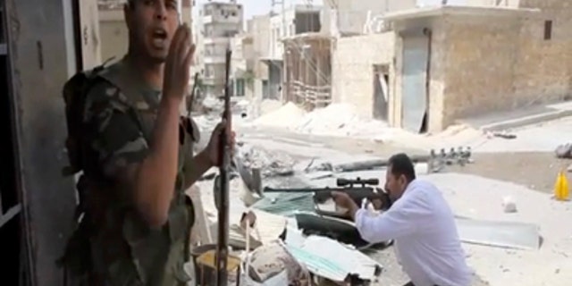 Sept. 1, 2012: In this image made from video and accessed a Free Syrian Army fighter calls out to comrades as another fighter fires at Syrian Army positions in Aleppo, Syria.