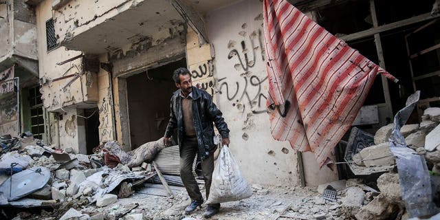 Dec. 2, 2012: In this photo, a man collects his belongings after his home was damaged due to heavy fighting between Free Syrian Army fighters and government forces in Aleppo, Syria.