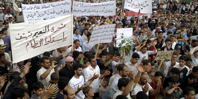 May 27: Syrian anti-regime protesters carry banners during a rally in Talbiseh, in the central province of Homs, Syria.