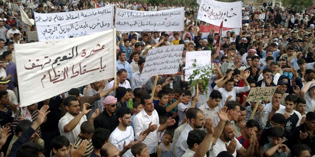 May 27: Syrian anti-regime protesters carry banners during a rally in Talbiseh, in the central province of Homs, Syria.