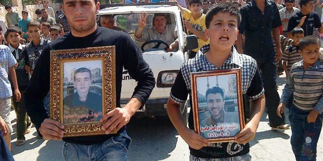 Anti-Syrian President Bashar Assad protesters hold portraits for their dead relatives killed in recent violence, as they march during a demonstration against the Syrian regime, at Maaret Harma village, in Edlib province, Syria, on Friday Sept. 9, 2011.