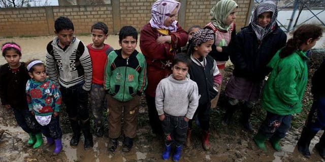 Syrian refugees pose for a photograph after their tents flooded from the rain at a temporary refugee camp in the eastern Lebanese town of Al-Faour near the border with Syria.