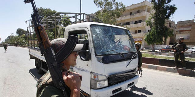 May 9, 2012: A Syrian army soldier secures the scene as he stands next to a military truck which was attacked by a roadside bomb, in Daraa city, southern Syria.