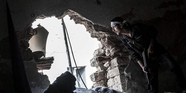 Oct. 24, 2012 photo: A Free Syrian Army fighter watches over an enemy position as rebel fighters belonging to the Liwa Al Tawhid group carry out a military operation at the Moaskar front line, one of the battlefields in the Karmal Jabl neighborhood, in Aleppo, Syria.