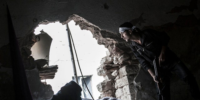 Oct. 24, 2012 photo: A Free Syrian Army fighter watches over an enemy position as rebel fighters belonging to the Liwa Al Tawhid group carry out a military operation at the Moaskar front line, one of the battlefields in the Karmal Jabl neighborhood, in Aleppo, Syria.