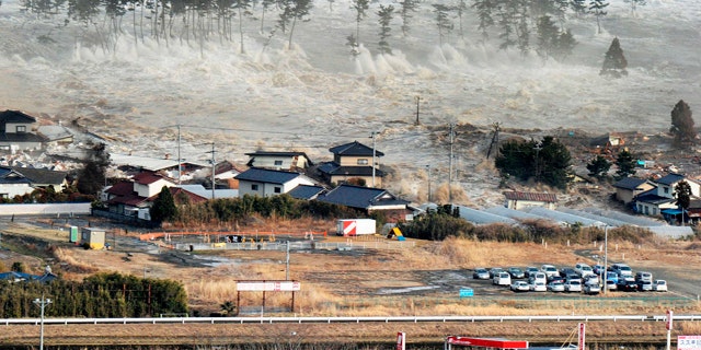 March 11: Waves of tsunami hit residences after a powerful earthquake in Natori, Miyagi prefecture.