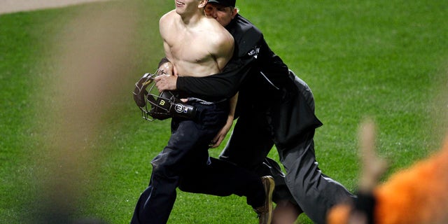 Umpire Jeff Kellogg, right, tackles a fan who ran onto the field in the middle of the seventh inning of a baseball game between the Oakland Athletics and the Baltimore Orioles in Baltimore, Friday, April 27, 2012. (AP Photo/Patrick Semansky)