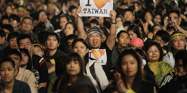 A protester displays a pro-Taiwan banner during a mass anti-China protest in front of the Presidential Building in Taipei, Taiwan.  Taiwan struggles with its identity as it retains its official name "People's Republic Of China," along with a constitution that defines its territory as covering all of mainland China.  But as far as communist China is concerned, Taiwan is part of its territory and insists on the reunification of the two sides.  (AP Photo/Wally Santana, file)