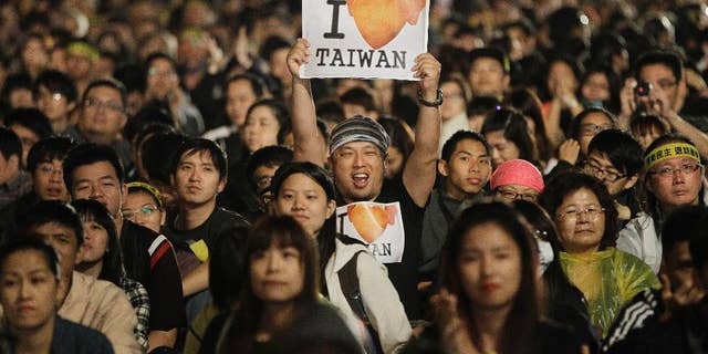 A protester displays a pro-Taiwan banner during a mass anti-China protest in front of the Presidential Building in Taipei, Taiwan. Taiwan struggles with its identity as it retains its official name "People's Republic Of China," along with a constitution that defines its territory as covering all of mainland China. But as far as communist China is concerned, Taiwan is part of its territory and insists on the reunification of the two sides. (AP Photo/Wally Santana, file)
