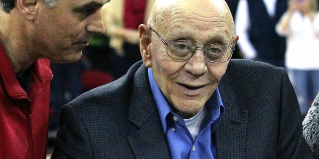 FILE - In this March 1, 2014, file photo, Jerry Tarkanian is escorted by his son, Danny, during halftime ceremonies honoring the former basketball coach at Fresno State University in Fresno, Calif. The Hall of Fame basketball coach is hospitalized in Las Vegas, where his son says he’s being treated for pneumonia. (AP Photo/Gary Kazanjian, File)