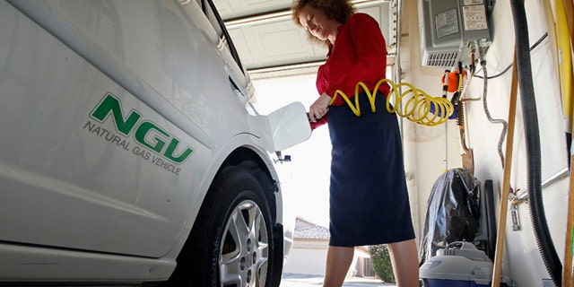 FILE: October 3, 2013. A woman connects the nozzle of a home refueling station to her 2003 natural gas powered Honda Civic, Chandler, Ariz.
